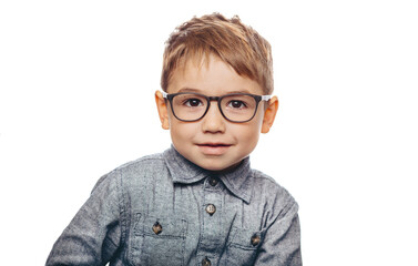 A young child with short hair and glasses smiles in a simple, bright background, showcasing a playful and confident demeanor