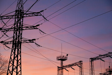 Silhouettes of power lines and structures stand out against a colorful sunset, creating a striking...