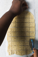Overhead view of crackers dough on parchment paper being sliced, cutting cracker biscuit dough on...