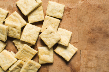 Overhead view of homemade crackers on a wood countertop, top view of freshly baked cracker biscuits, process of making crackers