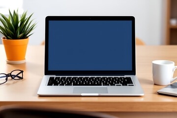 Fototapeta premium A modern workspace with a sleek laptop, a potted plant, and a coffee mug.