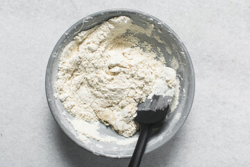 Overhead view of bagel dough being mixed in grey bowl, top view of homemade bagel dough being mixed in bowl, process of making bagels