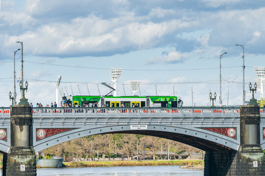 A electric commuter tram going over an historic arched bridge
