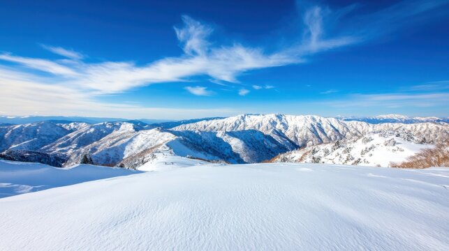 Panoramic view of snow-covered mountain range under a vibrant blue sky.