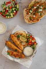 Chicken Kofta Kebab on wooden skewers with pita, garlic sauce Toum, parsley, lemon, cucumber and tomato. Shish kafta tavuk. Traditional Middle East food. Lebanese, Turkish cuisine. Food photography.