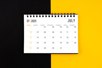 July 2025 desk calendar on black and yellow background, Flat lay.