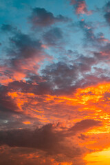 Partly cloudy sky with orange clouds at sunset in vertical photo