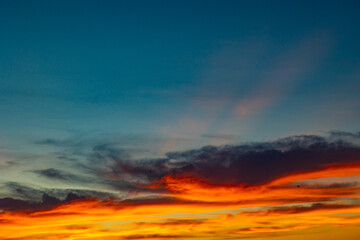 Dramatic orange clouds with sunrays at sunset.