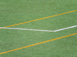 Obraz premium Green turf with yellow and white markings at a sports field during daytime