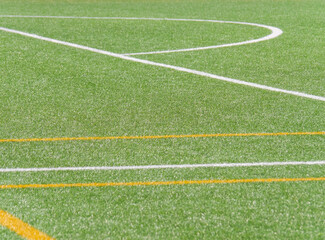 Green turf field marked with white and orange lines for sports activities and games
