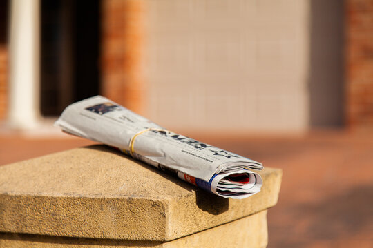 Newspaper rolled up and placed on mailbox in front of home