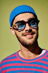 Obraz premium Young man showcases vibrant style in trendy sunglasses against a green backdrop