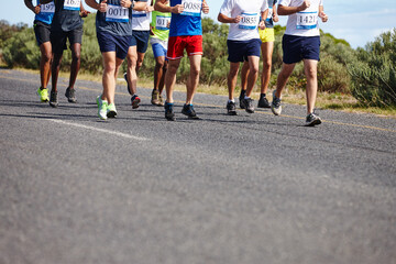 Marathon, legs and group running in road for competition, healthy body or cardio exercise. Low angle, race and athletes with fitness performance, sports contest or workout pace for endurance training