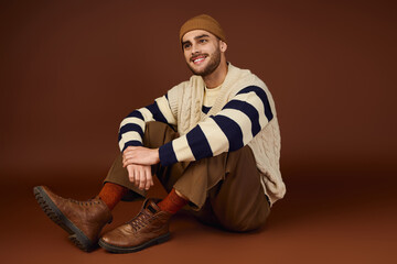 Young man showcases cozy winter style in a beanie and knitted sweater