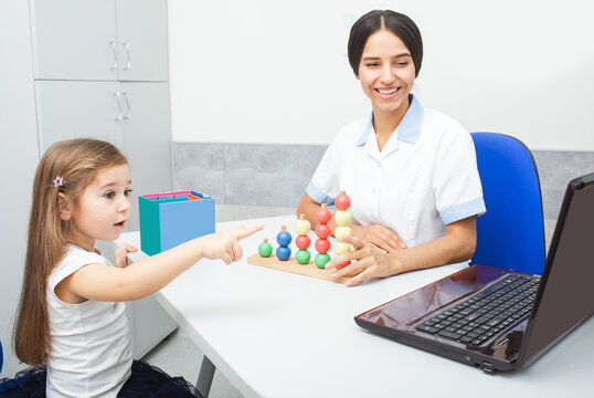 Child participates in playful learning activity with an occupational therapist in a bright therapy room while using a laptop