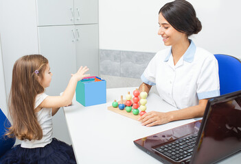 A child engages in a playful activity with colorful tools while an occupational therapist guides her through the session