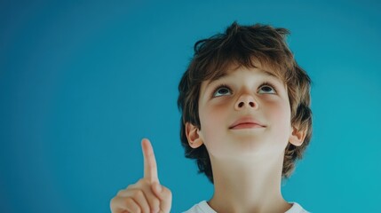 Photo of a boy's face against blue background, hands raised upwards.