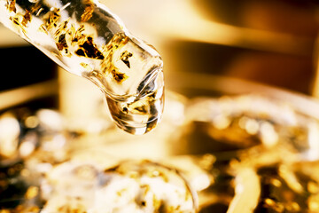 Obraz premium Pipette with Golden skincare serum with gold flakes for luxurious beauty treatments