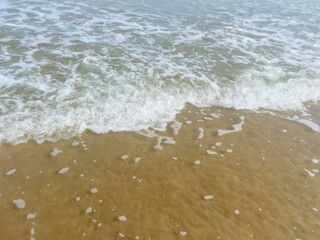 Natural sea water background, sandy seashore, sea water foam