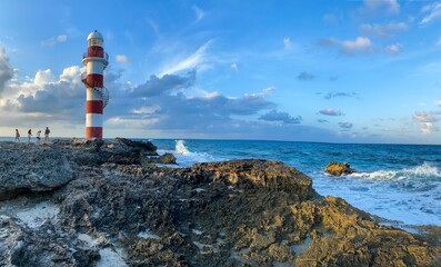 Red and white lighthouse standing on rocks on a beach in Cancun Mexico
