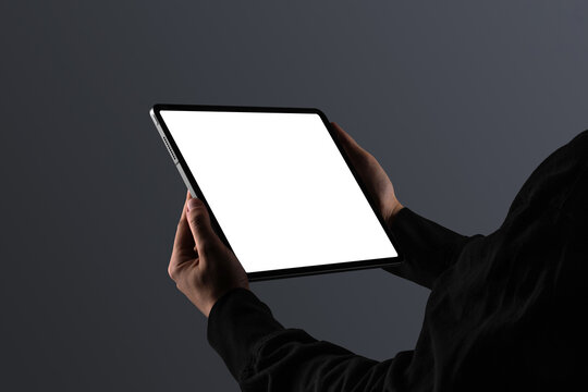A person dressed in black holding a tablet in landscape orientation. Isolated blank mockup surface to place your design. 