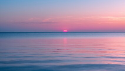 Obraz premium Serene sunset over calm water with soft pink and purple hues reflecting on the surface