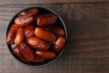 Tasty dried dates in bowl on wooden table, top view. Space for text