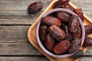 Many tasty dried dates in bowl on table, top view. Space for text