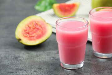 Refreshing guava juice and fresh fruits on grey table, closeup