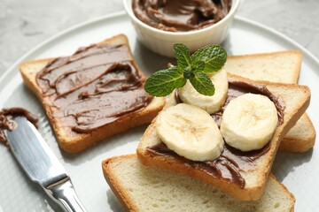 Sandwiches with chocolate butter, banana, mint and knife on table, closeup