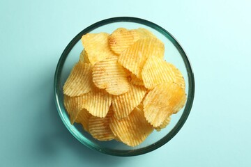 Tasty potato chips on light blue background, top view