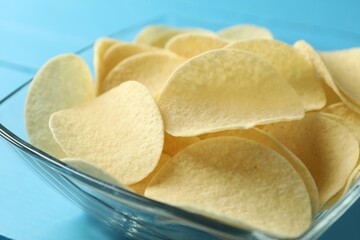 Tasty potato chips on blue table, closeup