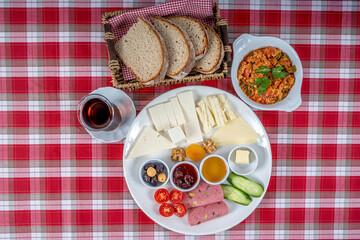 Traditional Turkish breakfast plate. The plate contains cheese varieties, jam, honey, eggs, tomatoes, cucumber, butter, olives and salami.