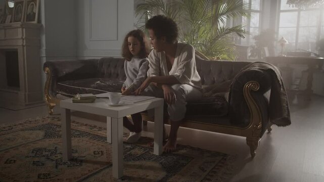 Young black mom teaching daughter sotsollfa syllables at home