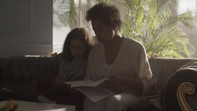 Focused mother and daughter looking at solfeggio music sheets