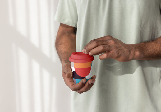 man Holding a Takeaway Paper Coffee Cup With Lid Indoors