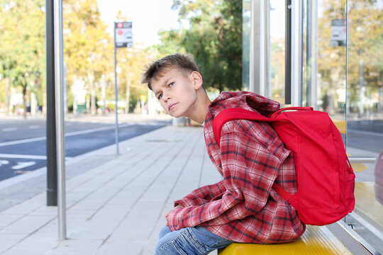 Teenager waiting the bus at the stop in the city