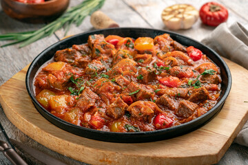 Beef stew in tomato sauce with vegetables and herbs in a frying pan