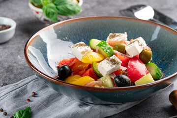 Vibrant Greek salad in a blue bowl, featuring tomatoes, cucumbers, olives, and feta cheese, sprinkled with herbs. Perfect for Mediterranean diet, ideal for healthy eating.