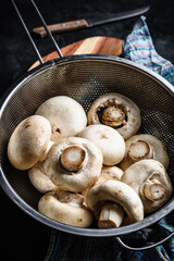 Button mushrooms in metal colander
