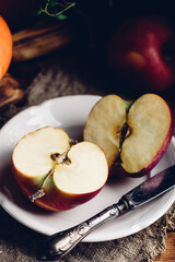 Two Halves of Red Apple on White Plate with Vintage Knife in Rustic Setting