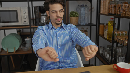 Fototapeta premium Young hispanic man stretches in an office with shelves filled with jars and dishes, suggesting a relaxed and friendly work environment.