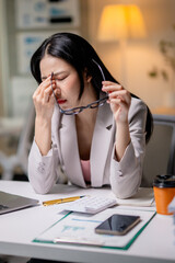 Tired asian manager feeling eye strain after using laptop computer working late at night