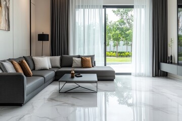 Obraz premium Modern living room with gray sectional sofa, coffee table, and large windows overlooking a garden. Sleek design with neutral tones and polished marble flooring.