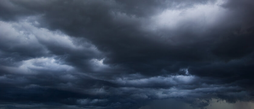 A dense, dark sky filled with swirling storm clouds signals an intense windstorm, emphasizing the power and drama of nature's environment in turbulent weather conditions.