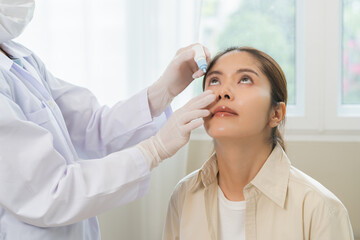 Health care concept, eye doctor eye drops to asian young woman patient, hand using medical eye drop to treat dry eye, suffering irritation or inflammation, allergy optical symptom at optic clinic.