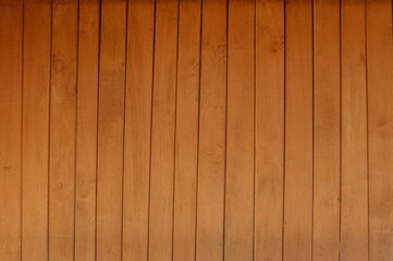 Obraz premium A smooth wooden wall featuring vertical planks in a warm, rich brown color, perfect for adding a cozy touch to any design project.