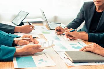 Business alliance groups by analyzing documents, discussing reports at the board meeting table. A multi-ethnic team is negotiating a project to develop a business strategy. Close-up image.