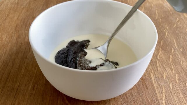 Pouring cream on traditional Finnish Easter Dessert M&auml;mmi in a white Ceramic Bowl