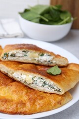 Tasty calzones with cheese and basil on table, closeup